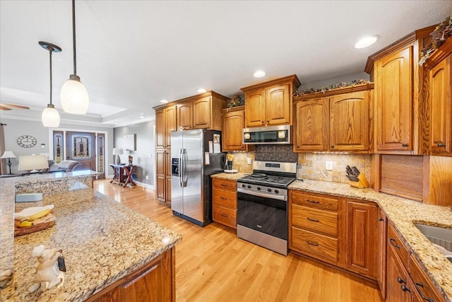 379 Hooper Rd, Winchester, TN 37398 - kitchen featuring stainless steel appliances, decorative backsplash, brown cabinetry, light wood-style flooring, and light stone countertops