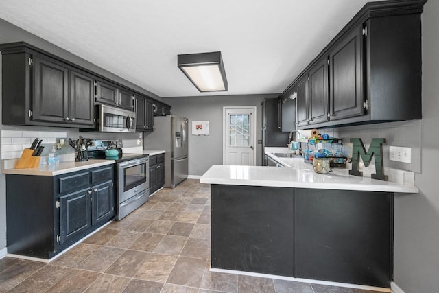 105 Gammons Ln, Lafayette, TN 37083 - kitchen with appliances with stainless steel finishes, a peninsula, dark cabinetry, light countertops, and decorative backsplash
