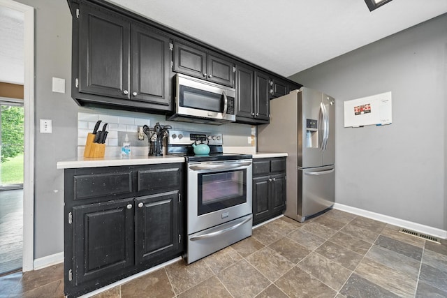 105 Gammons Ln, Lafayette, TN 37083 - kitchen featuring appliances with stainless steel finishes, dark cabinetry, light countertops, dark stone finish floors, and decorative backsplash