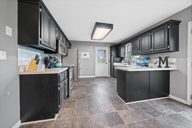 105 Gammons Ln, Lafayette, TN 37083 - kitchen featuring dark cabinetry, appliances with stainless steel finishes, light countertops, and a peninsula