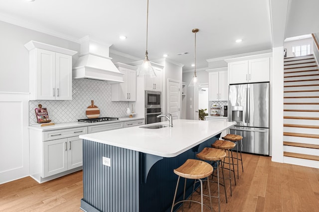 2636 Bramblewood Ln, Thompsons Station, TN 37179 - kitchen featuring appliances with stainless steel finishes, light wood-style flooring, an island with sink, backsplash, and white cabinets
