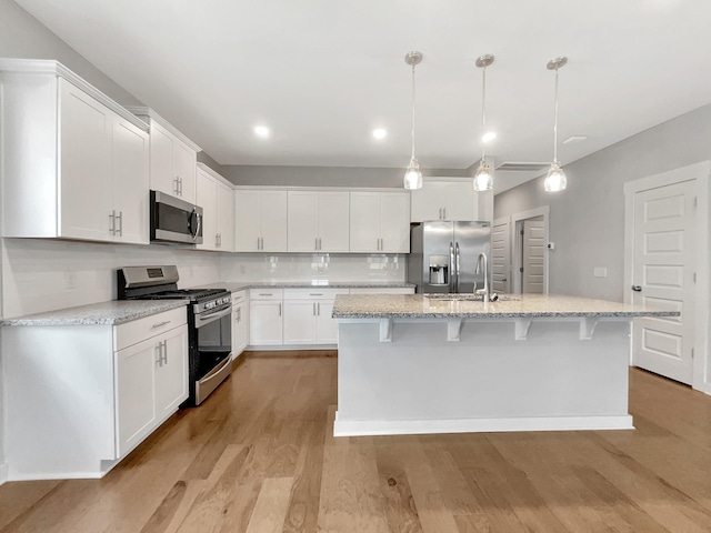 795 Ewell Farm Dr, Spring Hill, TN 37174 - kitchen with stainless steel appliances, white cabinetry, light wood-style floors, a center island with sink, and recessed lighting