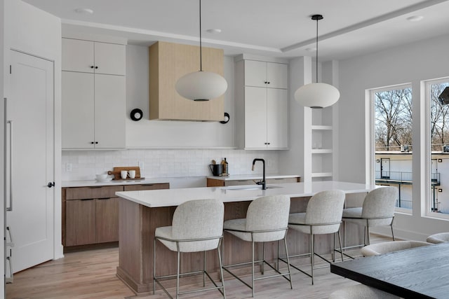 419 Acklen Park Dr, Nashville, TN 37205 - kitchen featuring light wood-style floors, decorative backsplash, light countertops, and a breakfast bar