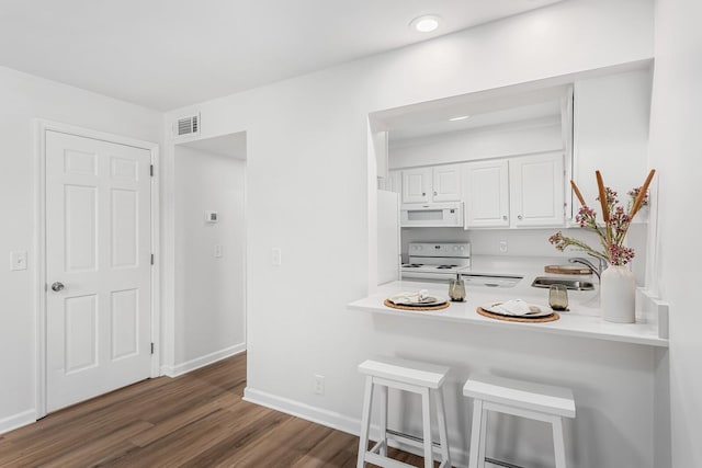 601 Boyd Mill Ave Unit O4, Franklin, TN 37064 - kitchen with white appliances, a kitchen bar, light countertops, white cabinets, and dark wood-style flooring