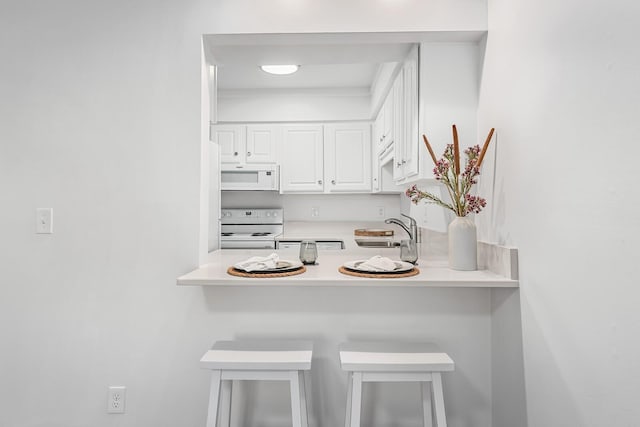601 Boyd Mill Ave Unit O4, Franklin, TN 37064 - kitchen featuring white appliances, white cabinets, a kitchen bar, light countertops, and a peninsula