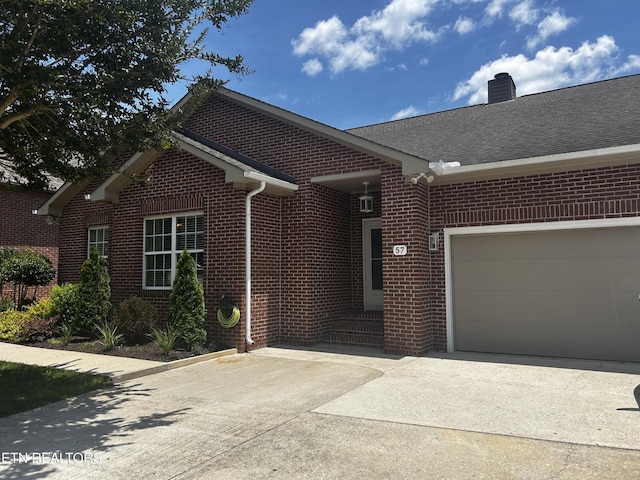 57 Riverview Dr, Oak Ridge, TN 37830 - view of front facade featuring brick siding, driveway, a garage, a chimney, and roof with shingles