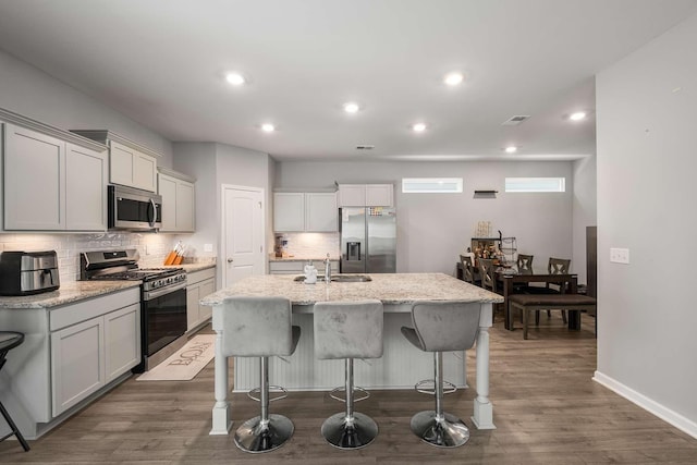 3210 Chatfield Dr, Murfreesboro, TN 37129 - kitchen featuring appliances with stainless steel finishes, backsplash, an island with sink, a kitchen bar, and dark wood-style floors