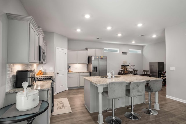 3210 Chatfield Dr, Murfreesboro, TN 37129 - kitchen featuring stainless steel appliances, an island with sink, decorative backsplash, dark wood-type flooring, and light stone countertops