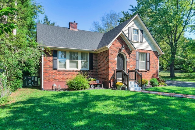 203 6th Ave, Columbia, TN 38401 - english style home featuring brick siding, a chimney, a front yard, and a shingled roof