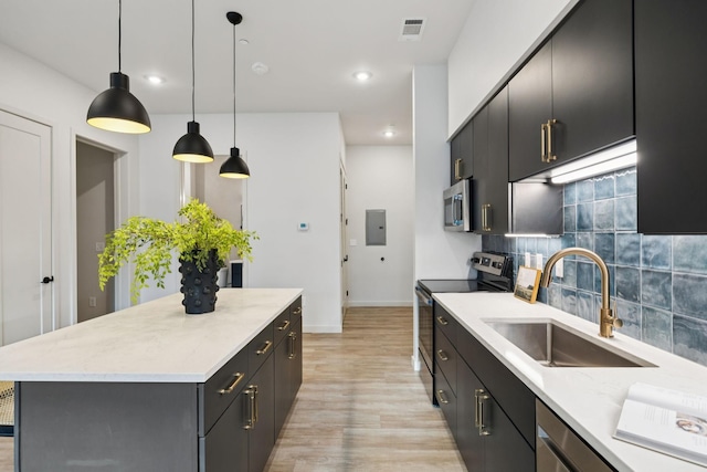 1014 16th Ave S Unit 103, Nashville, TN 37212 - kitchen with stainless steel appliances, decorative backsplash, light wood-style flooring, electric panel, and dark cabinetry