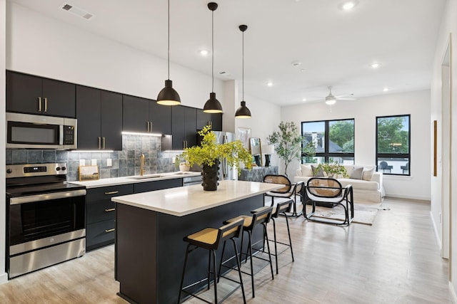1014 16th Ave S Unit 103, Nashville, TN 37212 - kitchen featuring stainless steel appliances, dark cabinets, a center island, light countertops, and recessed lighting