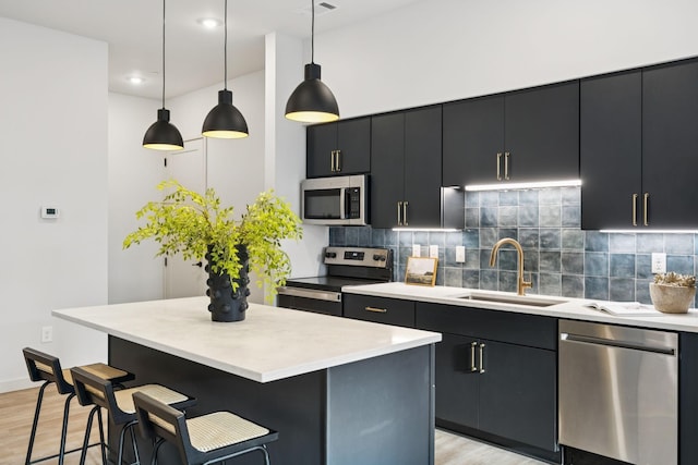 1014 16th Ave S Unit 103, Nashville, TN 37212 - kitchen featuring appliances with stainless steel finishes, dark cabinetry, light wood-style flooring, a center island, and a kitchen bar