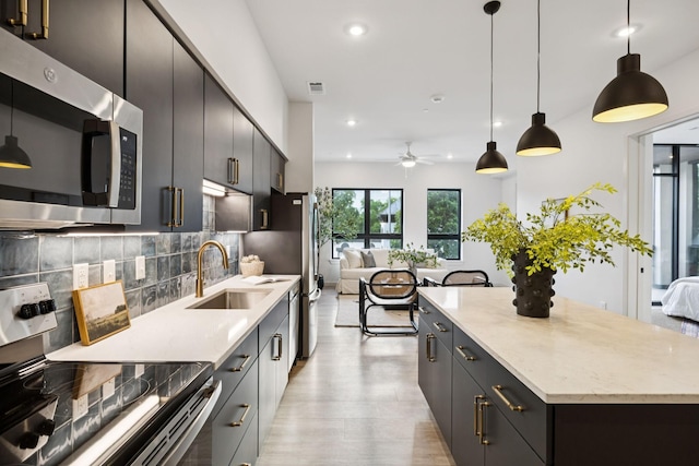 1014 16th Ave S Unit 103, Nashville, TN 37212 - kitchen with appliances with stainless steel finishes, recessed lighting, ceiling fan, decorative backsplash, and decorative light fixtures