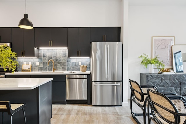 1014 16th Ave S Unit 103, Nashville, TN 37212 - kitchen with stainless steel appliances, dark cabinets, light countertops, hanging light fixtures, and tasteful backsplash