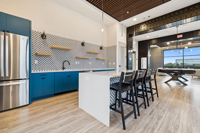 1014 16th Ave S Unit 103, Nashville, TN 37212 - kitchen with freestanding refrigerator, blue cabinetry, open shelves, and light countertops