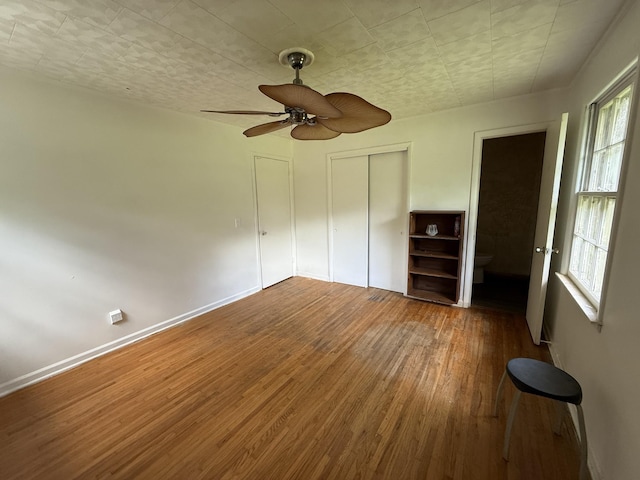 125 Benco Ln, Camden, TN 38320 - unfurnished bedroom featuring wood finished floors, multiple windows, a closet, and ceiling fan