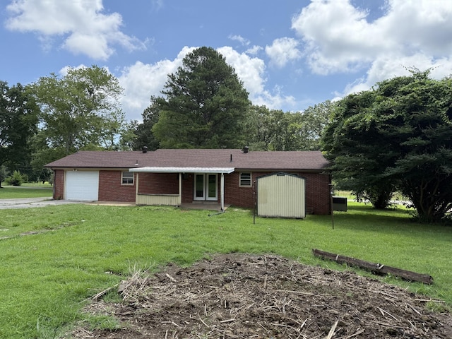 125 Benco Ln, Camden, TN 38320 - back of property with an attached garage, a lawn, brick siding, a storage shed, and driveway