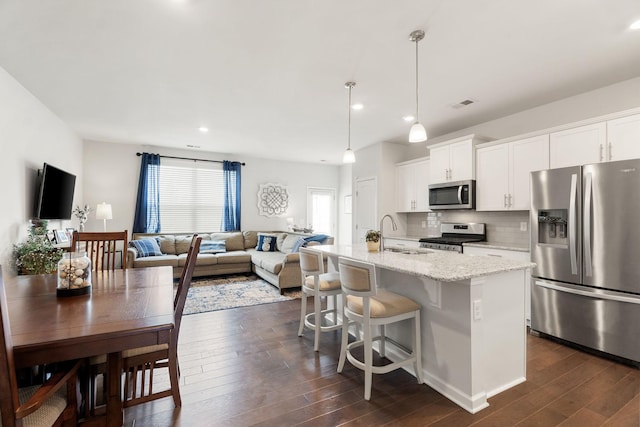 4206 Grapevine Loop, Smyrna, TN 37167 - kitchen with stainless steel appliances, dark wood-style floors, an island with sink, backsplash, and white cabinets