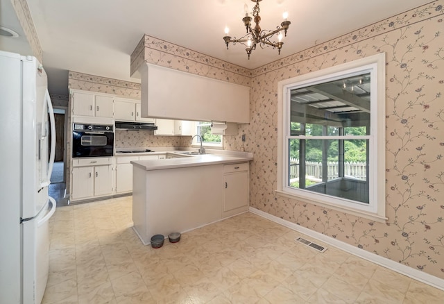 2208 Bowman Rd, Franklin, TN 37064 - kitchen featuring black appliances, under cabinet range hood, wallpapered walls, a chandelier, and a peninsula