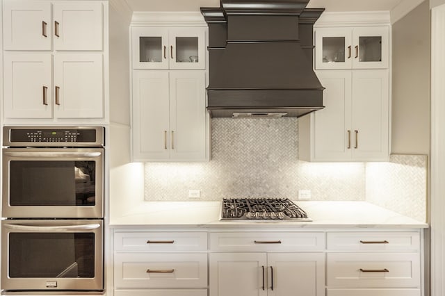 1328 Reynard Dr, Gallatin, TN 37066 - kitchen with appliances with stainless steel finishes, custom range hood, white cabinets, glass insert cabinets, and backsplash
