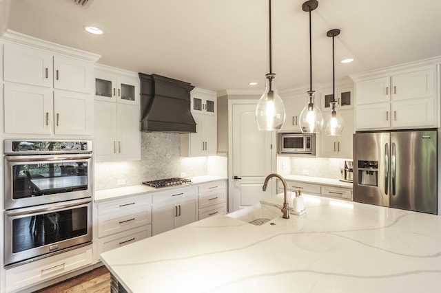 1328 Reynard Dr, Gallatin, TN 37066 - kitchen with stainless steel appliances, custom range hood, white cabinetry, glass insert cabinets, and recessed lighting