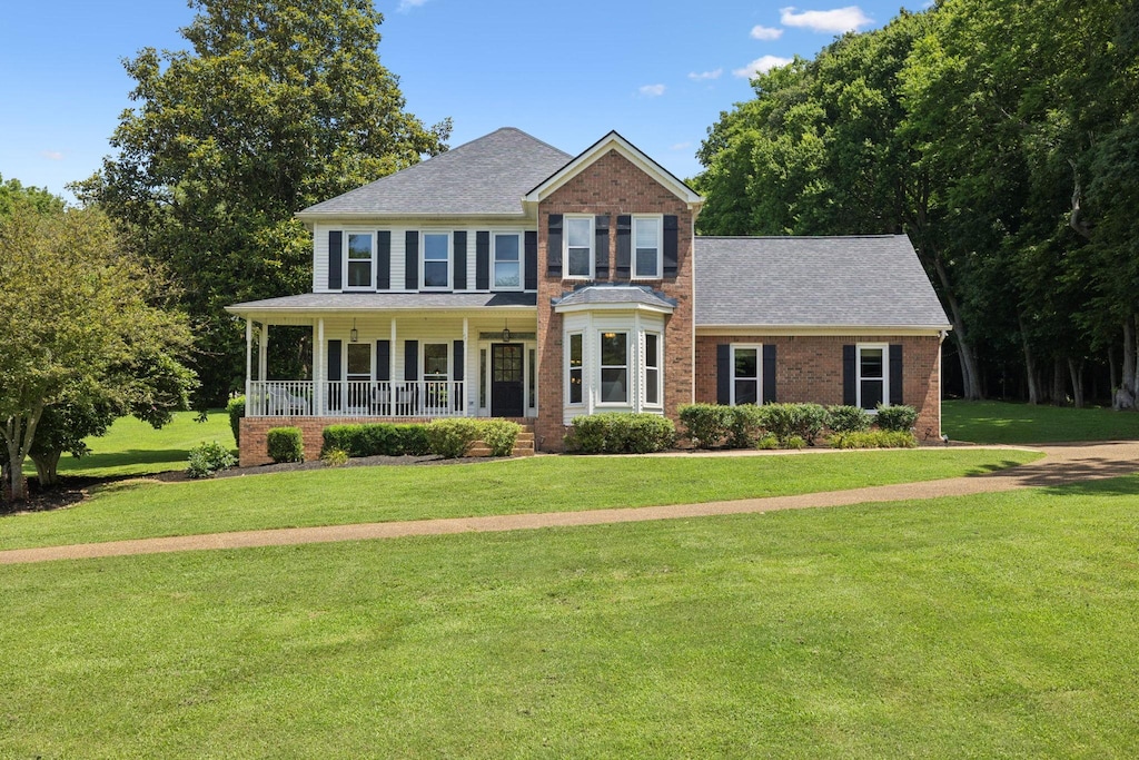 1420 Mayberry Ln, Franklin, TN 37064 - view of front of house with covered porch, a front yard, a shingled roof, and brick siding