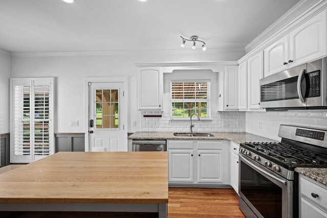 1204 Corlew Dr, Burns, TN 37029 - kitchen with stainless steel appliances, wooden counters, ornamental molding, white cabinetry, and backsplash