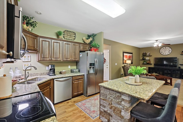 1511 Cardinal Ln, Mount Juliet, TN 37122 - kitchen featuring stainless steel appliances, open floor plan, light stone countertops, light wood-style flooring, and a kitchen breakfast bar