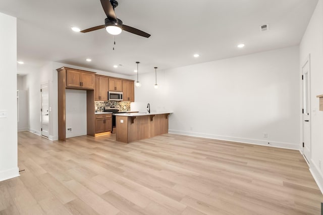 11 Dutch Dr, Clarksville, TN 37043 - kitchen featuring stainless steel appliances, a kitchen breakfast bar, brown cabinets, a ceiling fan, and a peninsula