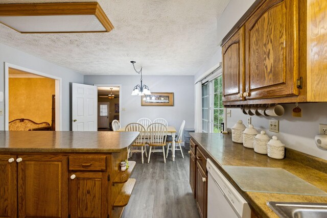 219 Lakeview Dr, Hohenwald, TN 38462 - kitchen with white dishwasher, dark wood finished floors, a chandelier, dark countertops, and a textured ceiling