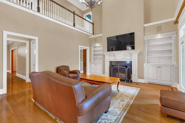 1512 Mirabella Way, Murfreesboro, TN 37130 - living area with a high ceiling, built in shelves, a chandelier, a fireplace with raised hearth, and wood finished floors