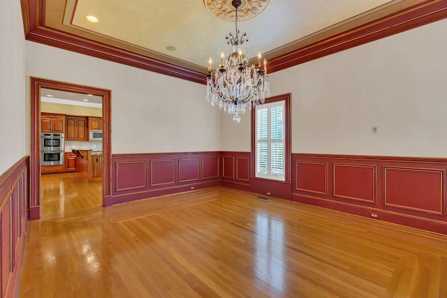 1512 Mirabella Way, Murfreesboro, TN 37130 - empty room featuring crown molding, a chandelier, a wainscoted wall, light wood finished floors, and a decorative wall