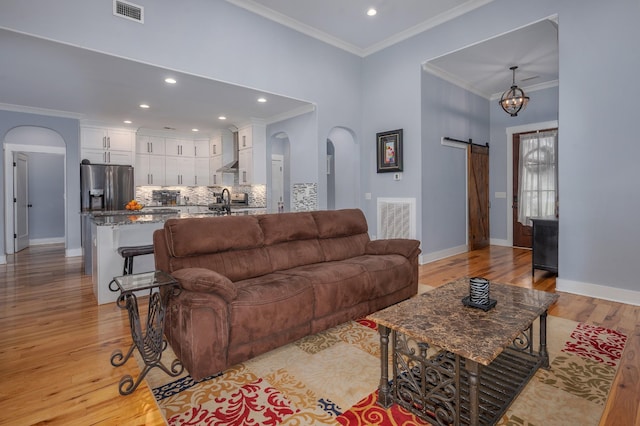 822 Manner Ln, Lebanon, TN 37087 - living room featuring arched walkways, ornamental molding, light wood-style flooring, a barn door, and recessed lighting