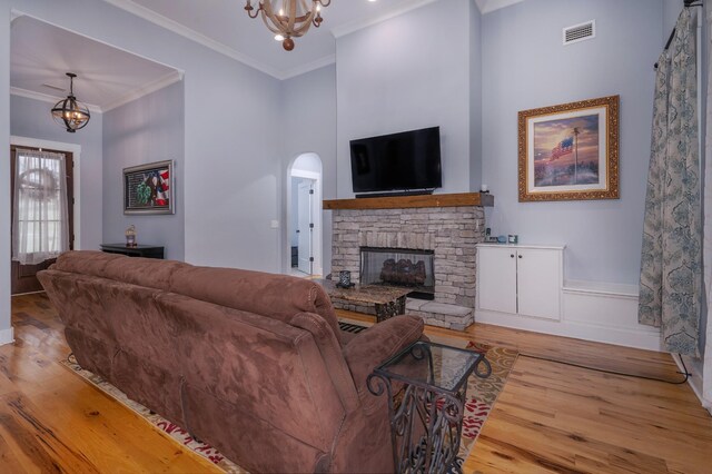 822 Manner Ln, Lebanon, TN 37087 - living room featuring a chandelier, wood finished floors, a stone fireplace, arched walkways, and crown molding