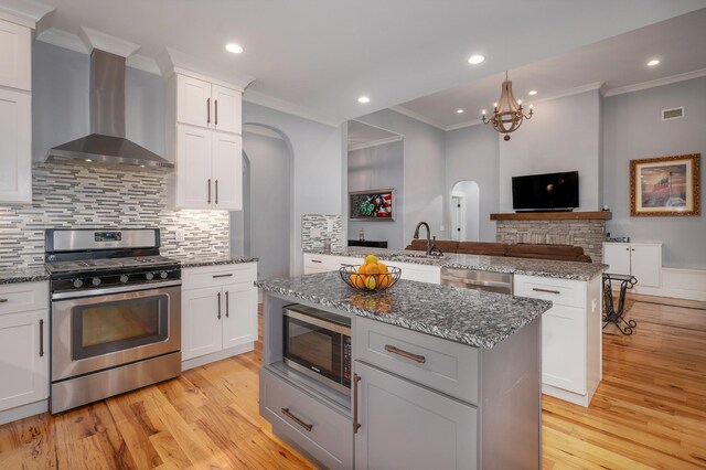 822 Manner Ln, Lebanon, TN 37087 - kitchen with appliances with stainless steel finishes, wall chimney range hood, arched walkways, crown molding, and light wood finished floors
