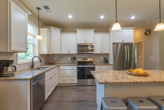 7929 Ridgewood Rd, Goodlettsville, TN 37072 - kitchen with appliances with stainless steel finishes, white cabinets, dark wood-style flooring, a kitchen breakfast bar, and recessed lighting