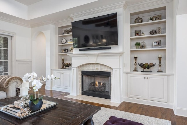 7216 Wildings Blvd, College Grove, TN 37046 - living room featuring a tile fireplace, built in shelves, wood finished floors, and ornamental molding