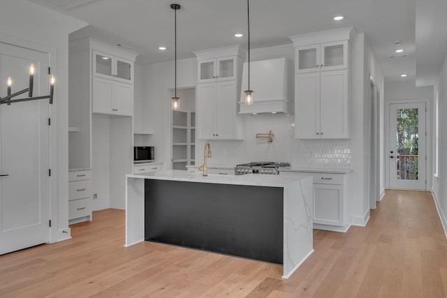 1117 38th Ave N Unit B, Nashville, TN 37209 - kitchen with stainless steel microwave, custom range hood, light countertops, light wood-style flooring, and white cabinets