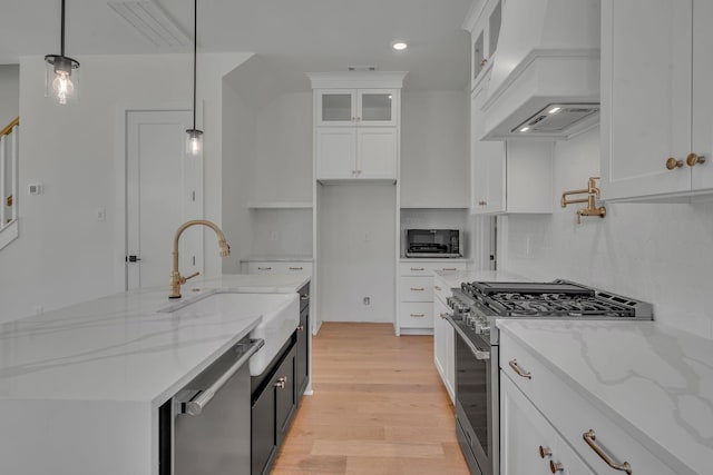 1117 38th Ave N Unit B, Nashville, TN 37209 - kitchen featuring appliances with stainless steel finishes, premium range hood, white cabinets, light wood finished floors, and glass insert cabinets