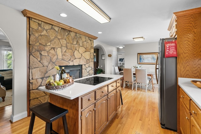 3406 Parks Ln, Spring Hill, TN 37174 - kitchen with freestanding refrigerator, black electric stovetop, arched walkways, light wood-style floors, and light countertops