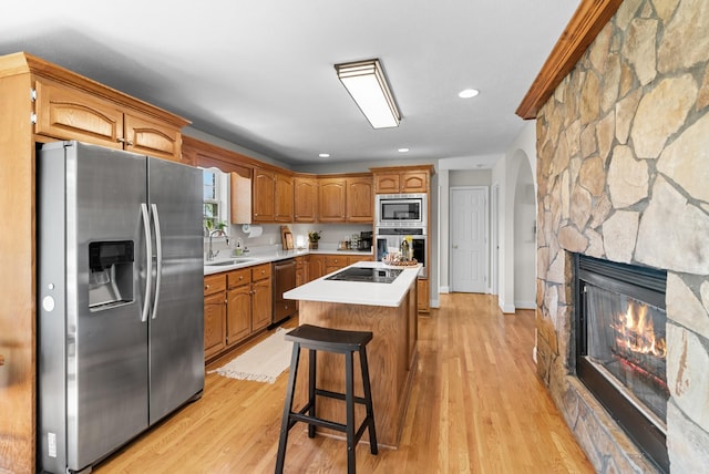 3406 Parks Ln, Spring Hill, TN 37174 - kitchen with stainless steel appliances, arched walkways, a kitchen island, light countertops, and a stone fireplace