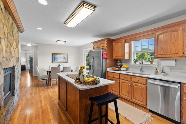 3406 Parks Ln, Spring Hill, TN 37174 - kitchen featuring appliances with stainless steel finishes, a center island, light countertops, a stone fireplace, and a breakfast bar area