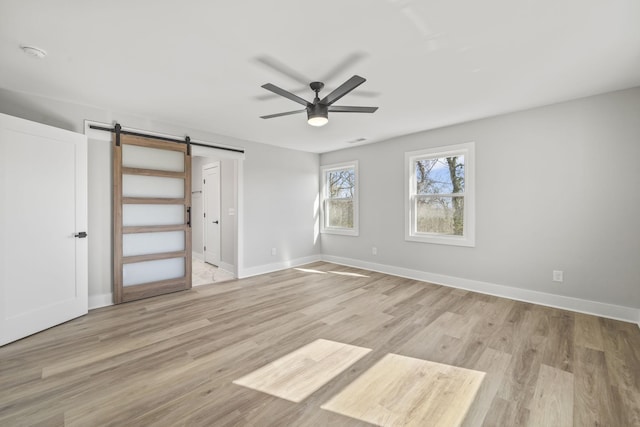 6608 Brookmont Ter, Nashville, TN 37205 - unfurnished bedroom featuring a barn door, light wood-style floors, and a ceiling fan