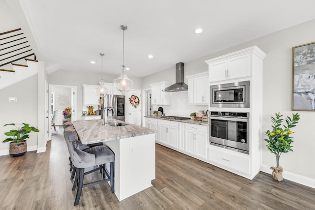 329 Clarabelle Ln, Clarksville, TN 37040 - kitchen with appliances with stainless steel finishes, wall chimney exhaust hood, an island with sink, wood finished floors, and recessed lighting