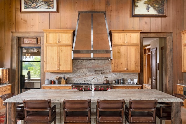 6971 W Cove Rd, Chickamauga, GA 30707 - kitchen with custom exhaust hood, wood walls, backsplash, a breakfast bar, and a center island with sink