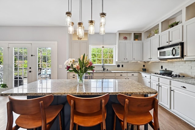 1209 Firth Ct, Franklin, TN 37067 - kitchen featuring stainless steel microwave, gas cooktop, decorative backsplash, and white cabinetry