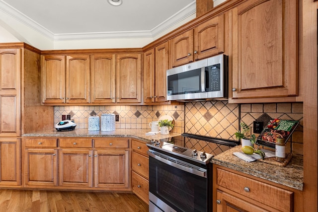203 Tom Robinson Rd, Franklin, TN 37064 - kitchen with appliances with stainless steel finishes, brown cabinetry, light wood-type flooring, crown molding, and decorative backsplash