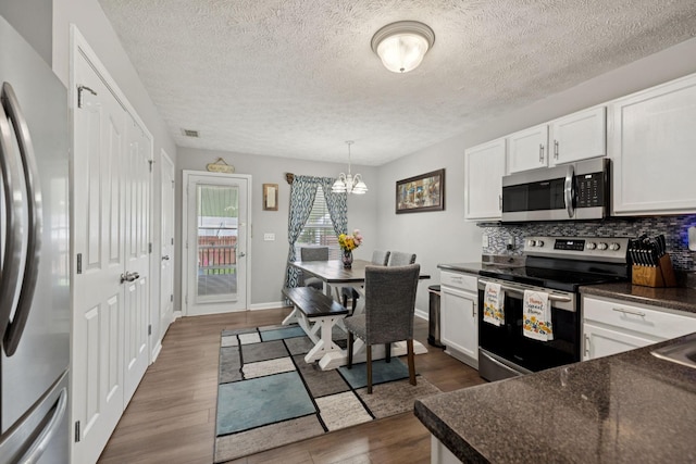 1804 Cason Trl, Murfreesboro, TN 37128 - kitchen with appliances with stainless steel finishes, dark countertops, dark wood-style floors, a chandelier, and decorative backsplash