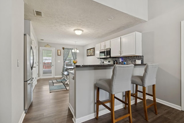 1804 Cason Trl, Murfreesboro, TN 37128 - kitchen featuring appliances with stainless steel finishes, a peninsula, dark countertops, white cabinets, and a textured ceiling