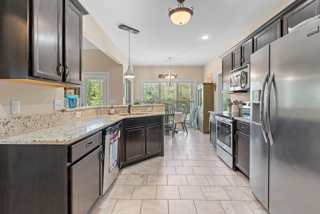 1372 Tidwell Switch Rd, Dickson, TN 37055 - kitchen with stainless steel appliances, light stone counters, a chandelier, pendant lighting, and dark brown cabinets